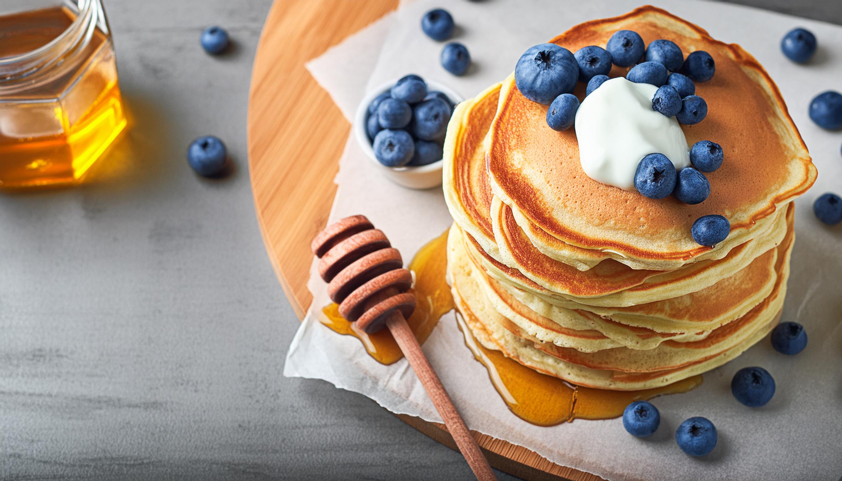 Volkoren tarwemeel pannenkoekjes met blauw bessen, honing en zure room